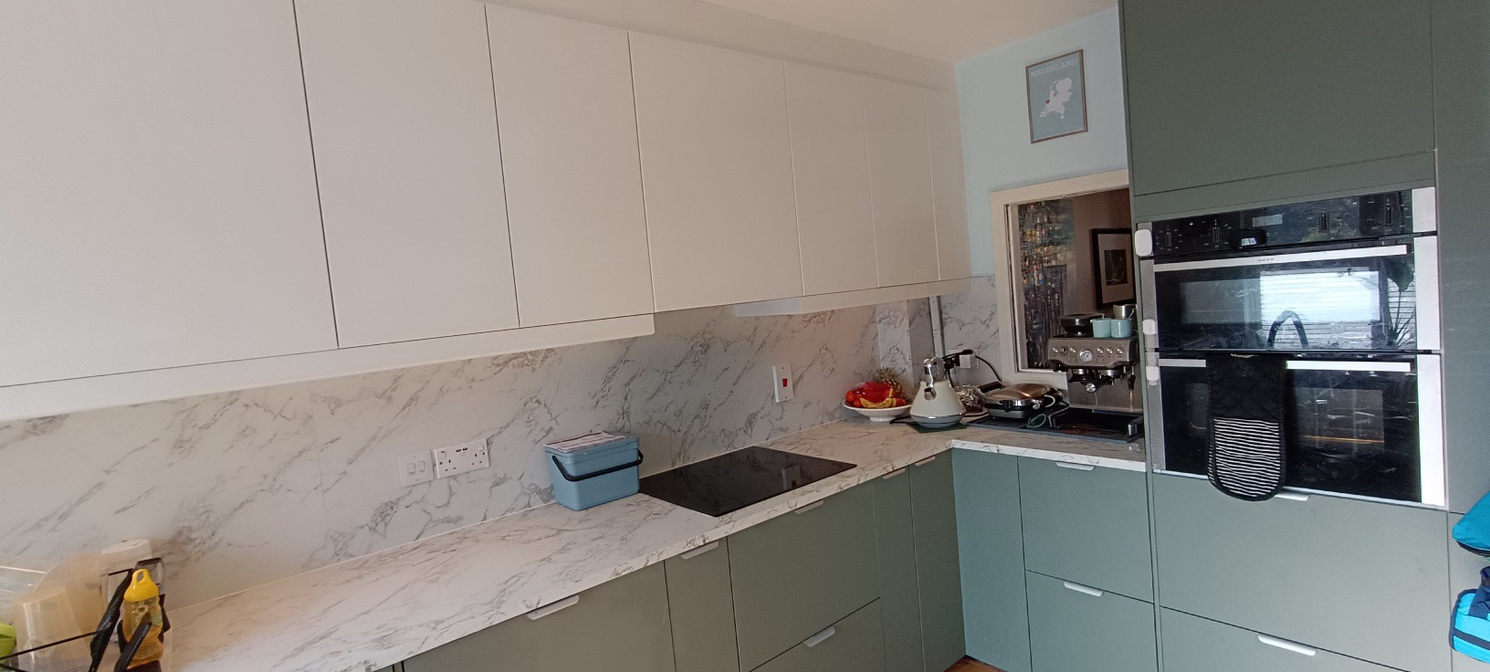 Sage green kitchen with marble splashback and integrated oven